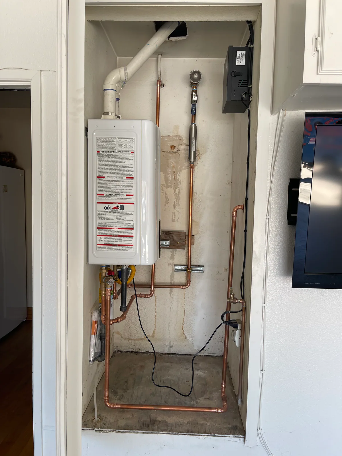 After: newly installed wall-mounted tankless water heater with updated piping