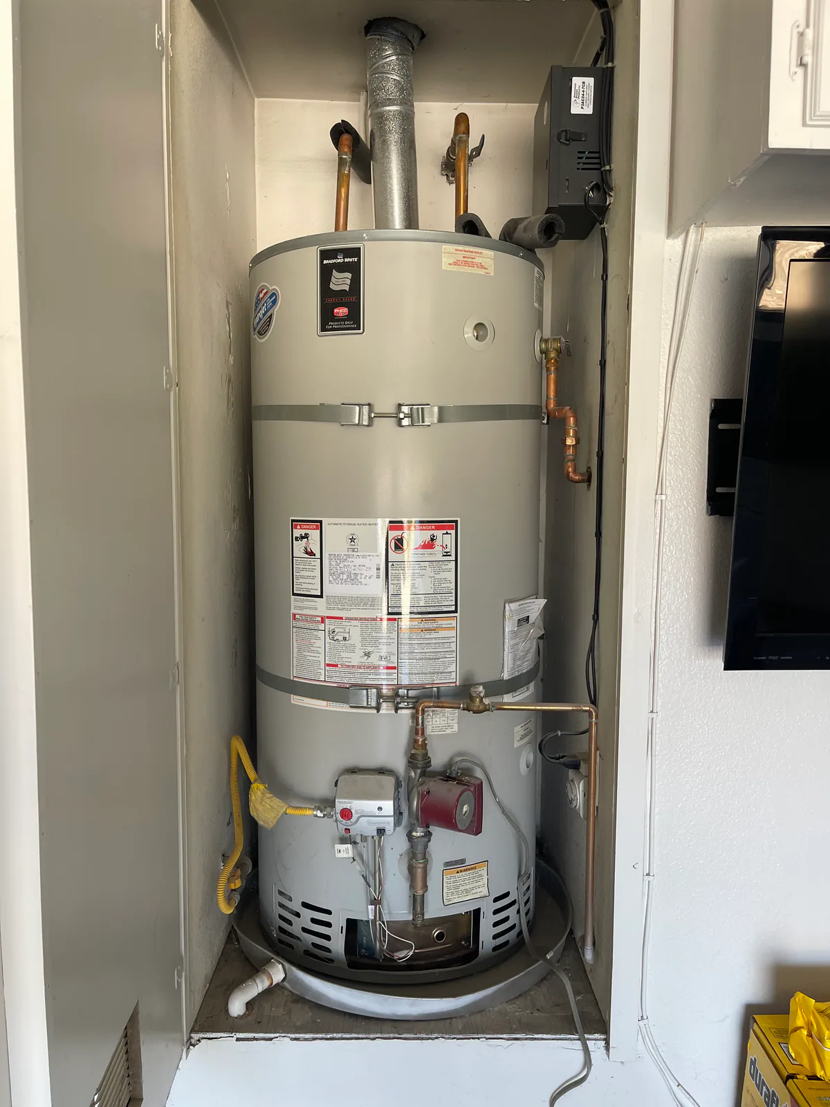 Before: existing 75-gallon tank water heater in a utility closet