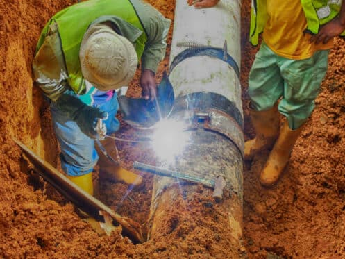 Workers operating on a dug up sewer pipe.